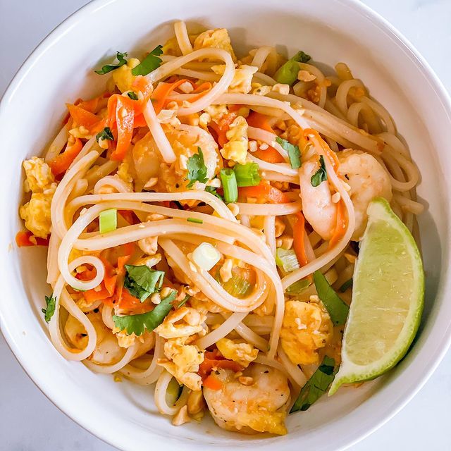 A bowl of pad thai noodles with sauteed veggies and egg.
