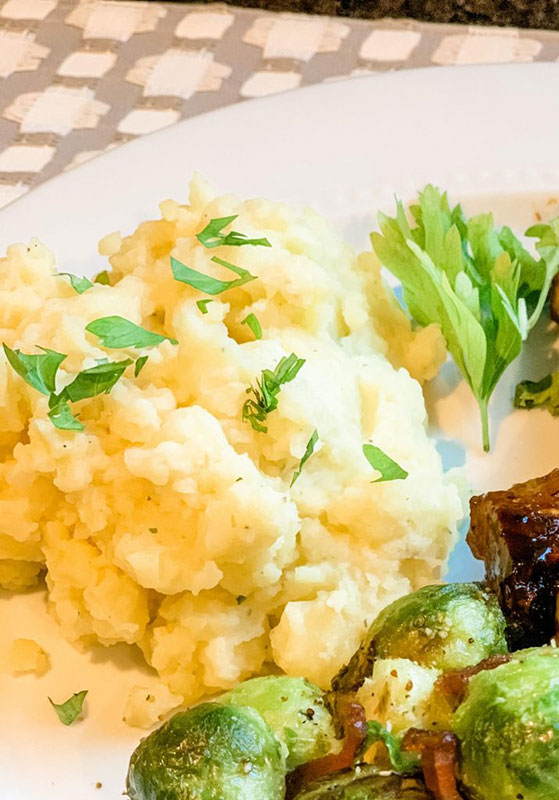 Mashed potatoes garnished with parsley on a plate.