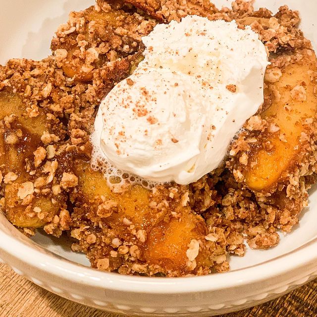 A bowl of warm apple crisp served with vanilla ice cream