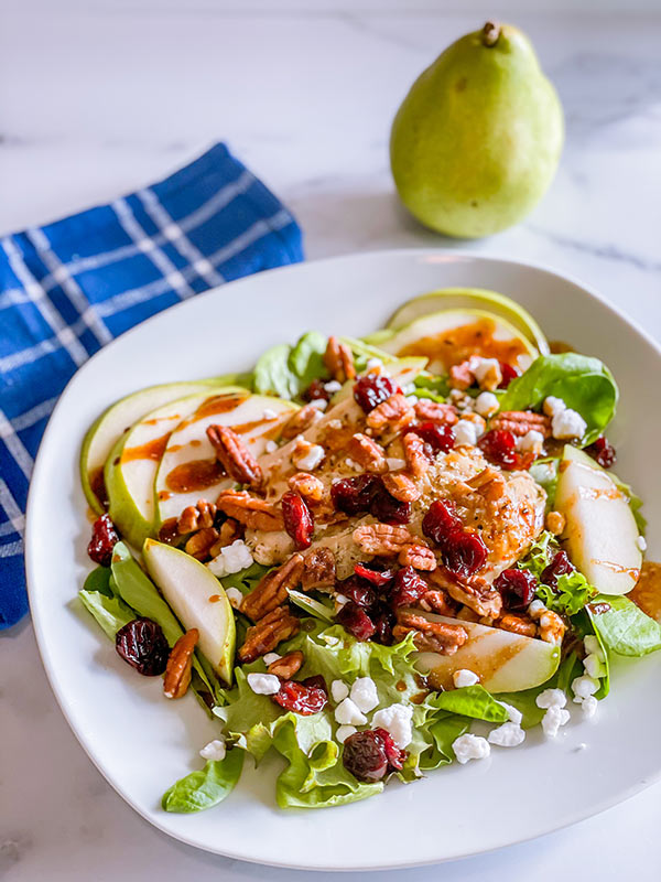 A colorful balsamic pear salad with dressing on a plate.