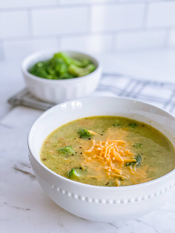 A bowl of broccoli cheese soup served with extra cheese on top.