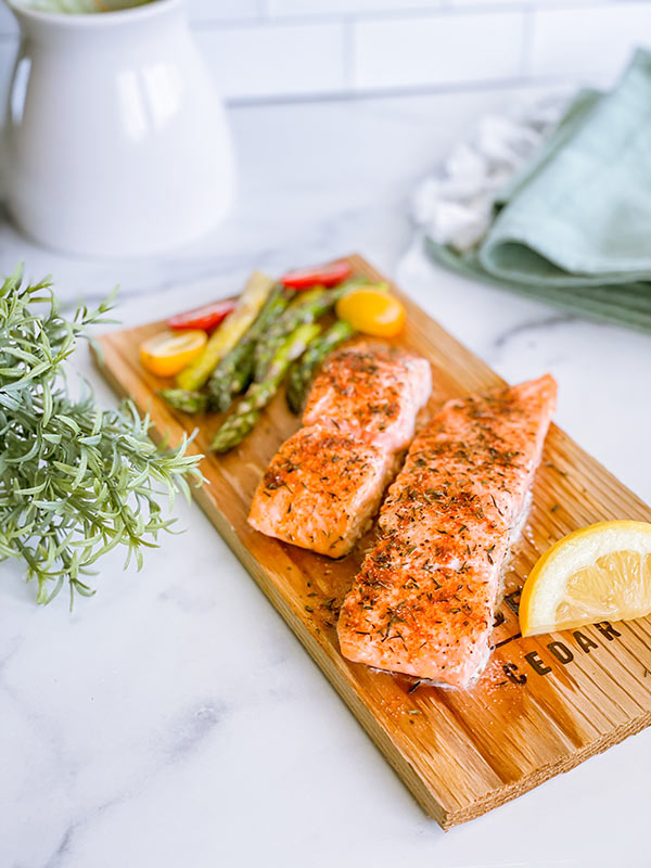 Salmon served with a side of vegetables and a lemon.