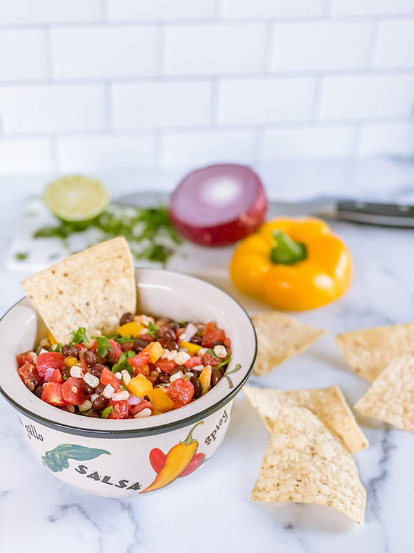 A bowl of black bean and corn salsa served with tortilla chips.