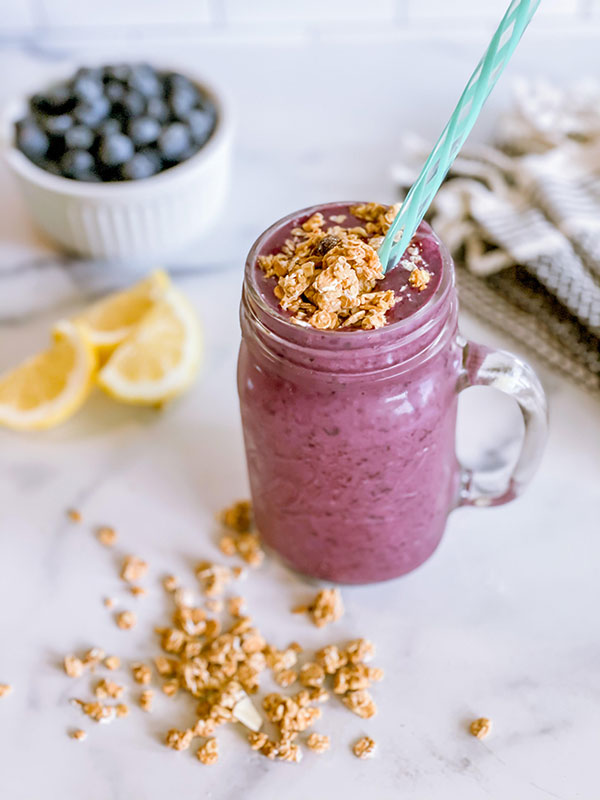 A blueberry cobbler smoothie served in a mason jar with granola on top.