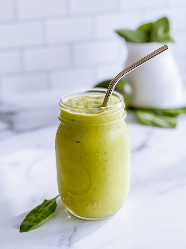 A green power smoothie in a mason jar with a straw.